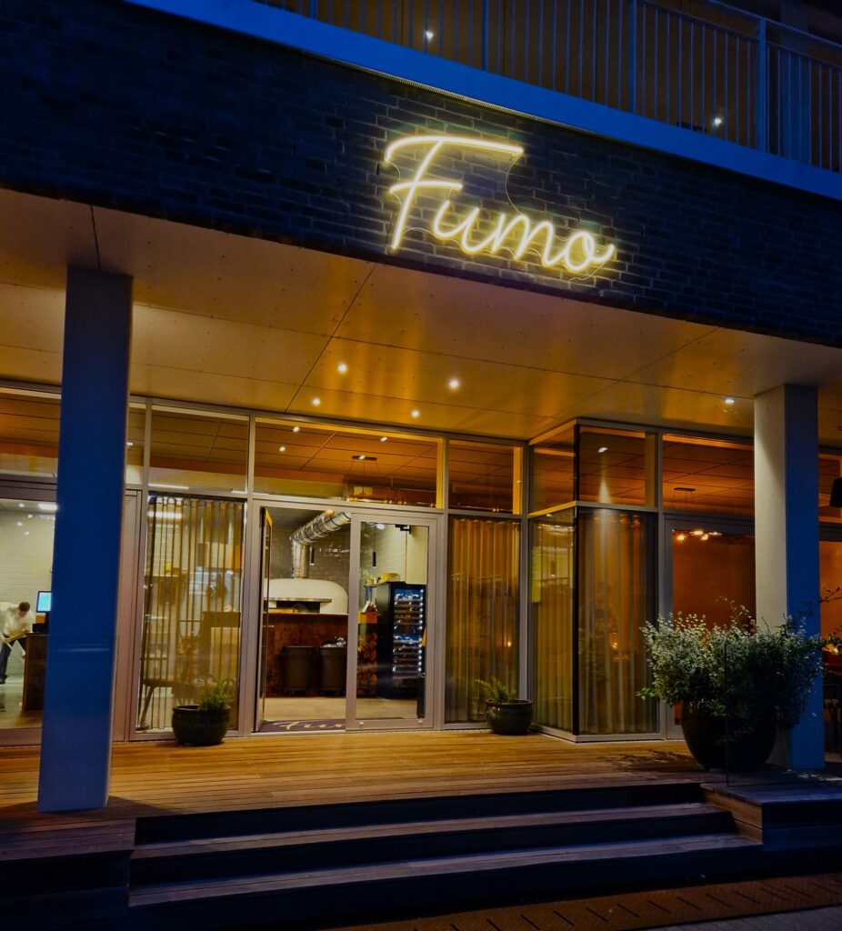 Neonskiltet Fumo over restaurantindgang om aftenen