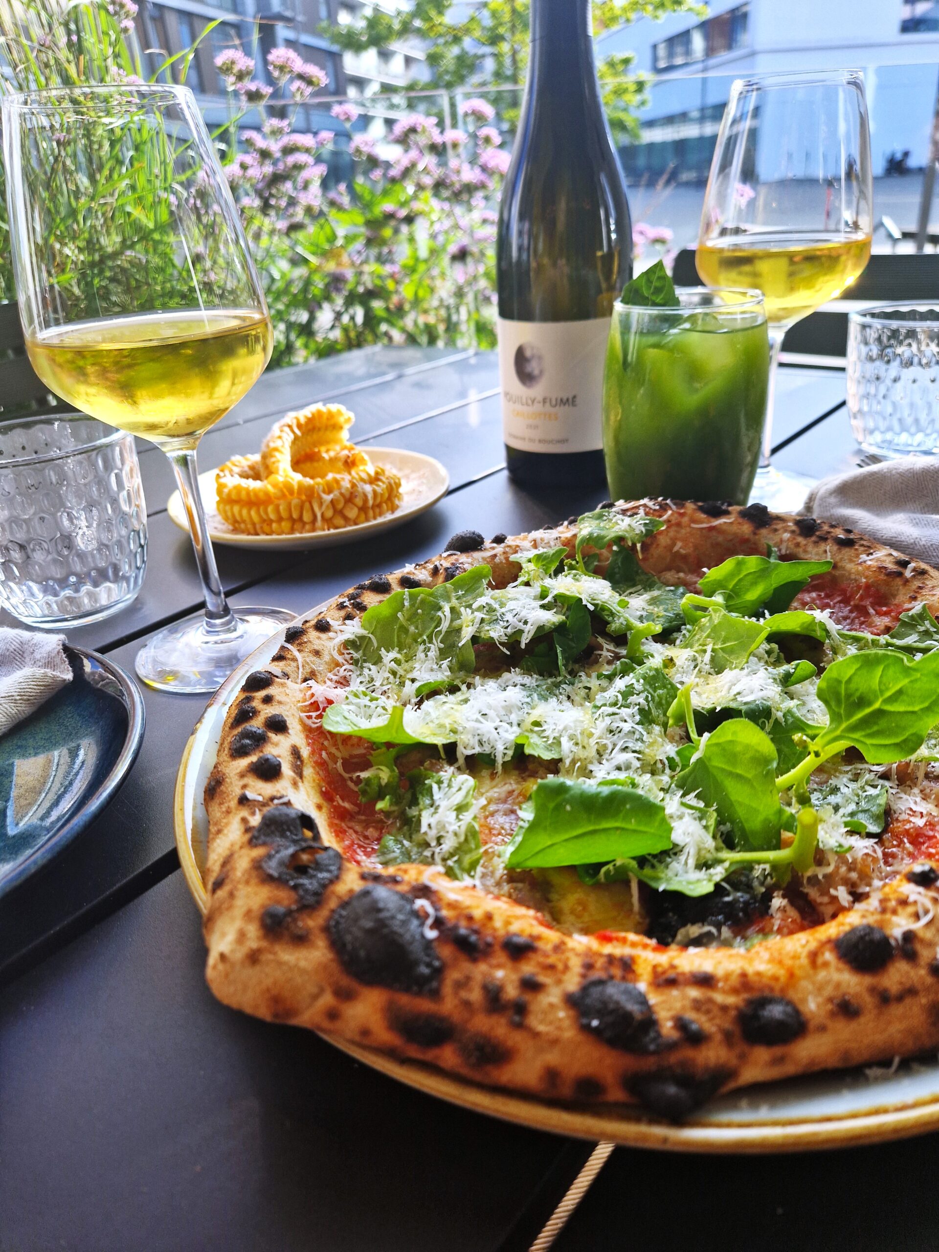 Pizza med rucola og hvidvin på udendørs café