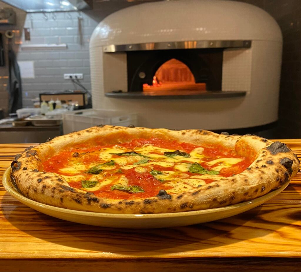 Margherita pizza foran brændefyret stenovn