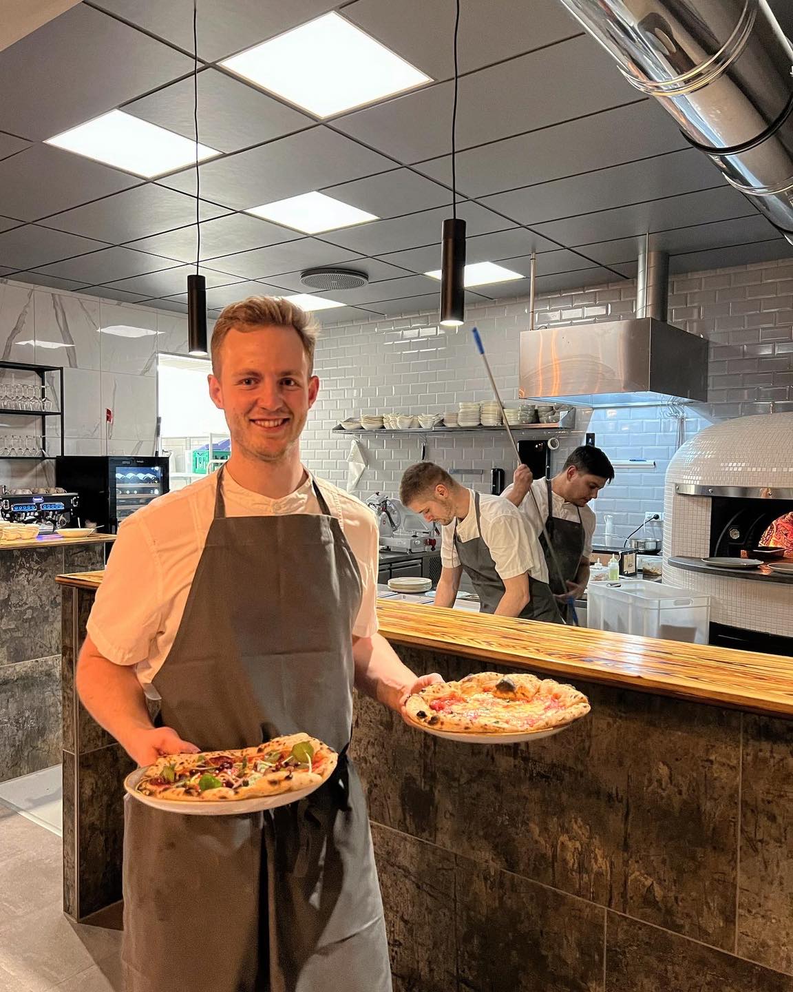 Kok med to pizzaer i restaurantkøkken