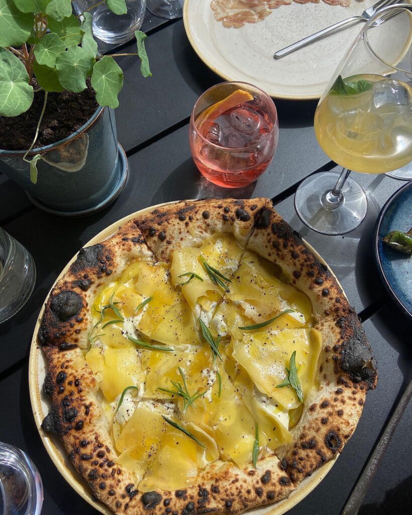 Pizza med osteflager og rosmarin på bord