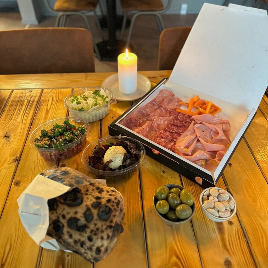 Charcuteribræt med pølser, brød og oliven på bord