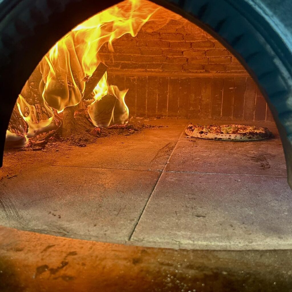 Pizza i brændefyret ovn med flammer