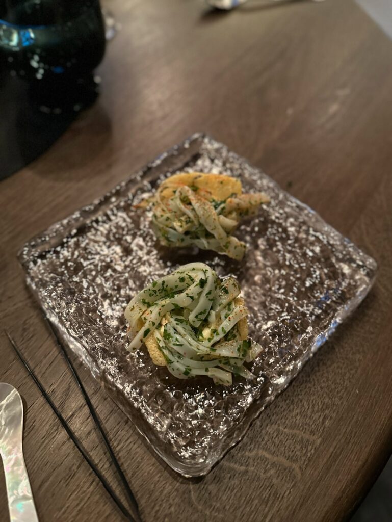 To små appetizers med blæksprutte på glasfad