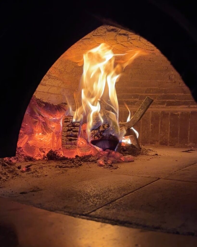 Brændende træ i muret ovn med gløder