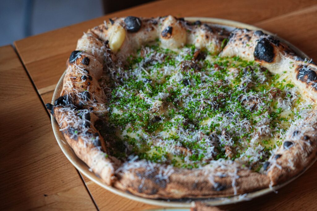 Gourmetpizza med grønne urter og revet ost