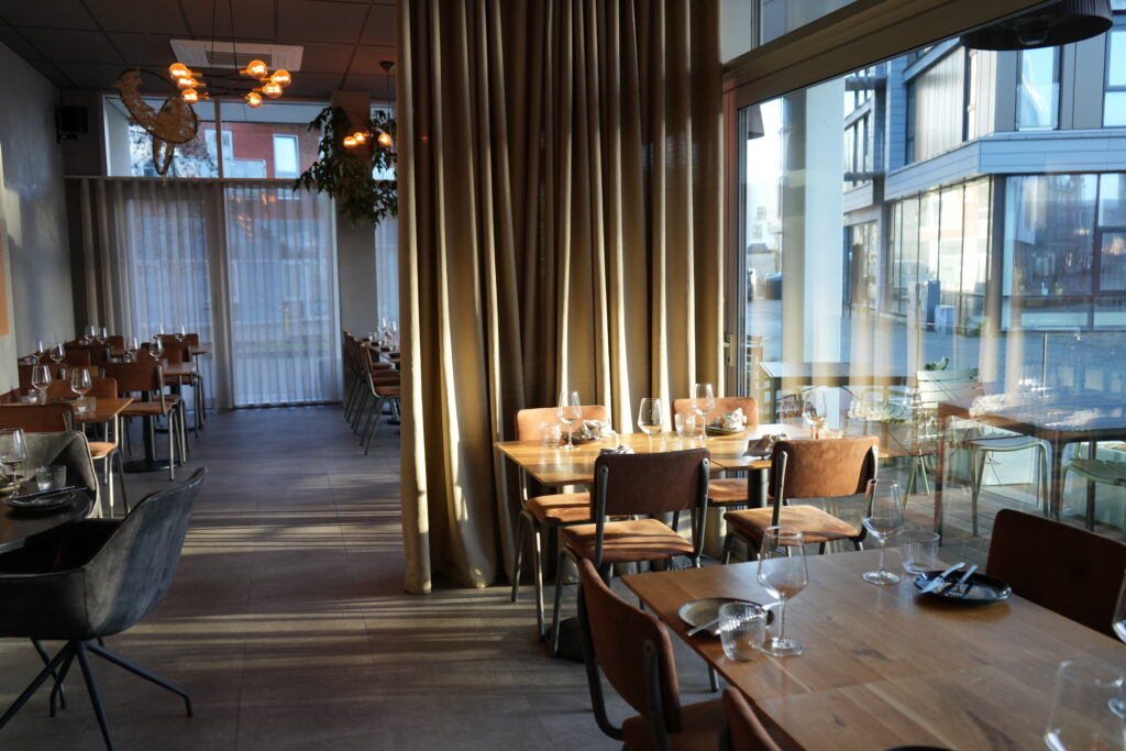 Moderne restaurant med træborde og store vinduer