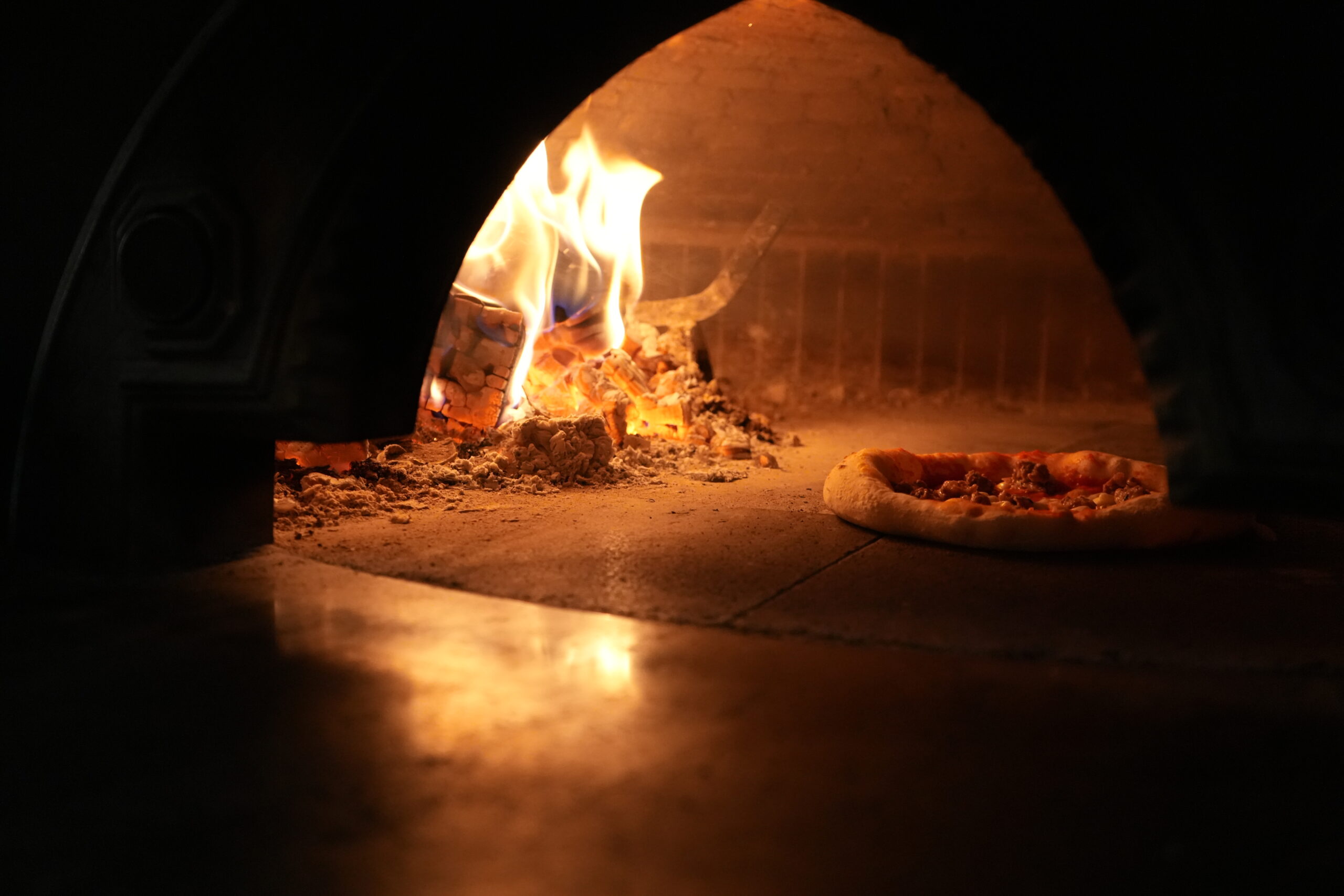 Pizza bages i brændefyret stenovn med flammer