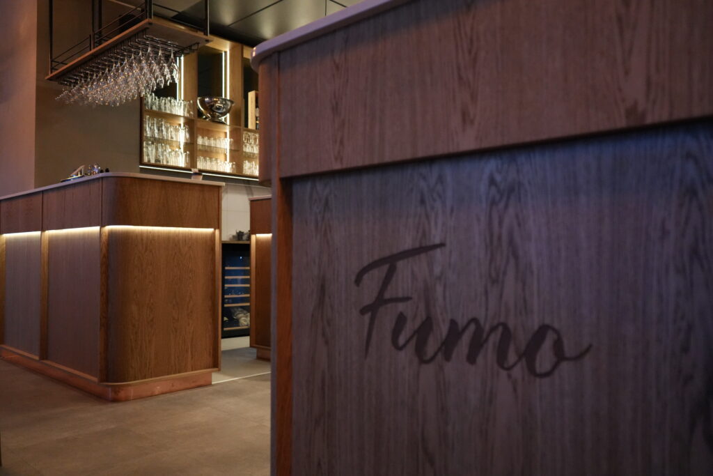 Moderne træbar med vinglas og Fuumo-skilt